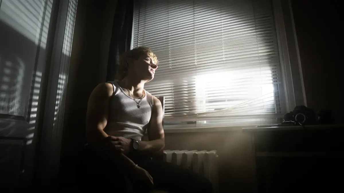 A man sitting in front of a window in a dark room