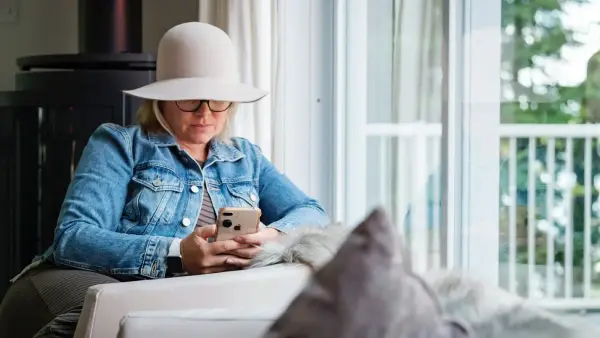 woman in blue denim jacket and gray hat sitting on white chair