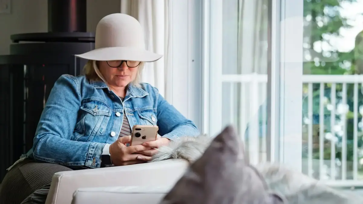 woman in blue denim jacket and gray hat sitting on white chair